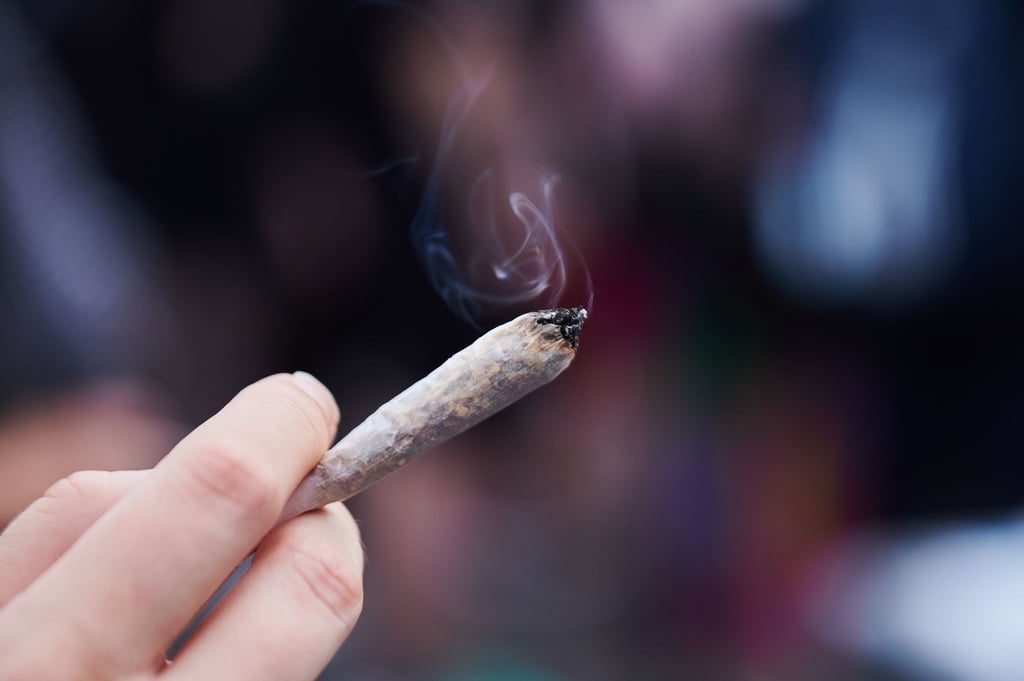 Eine Frau hält einen Joint in der Hand.