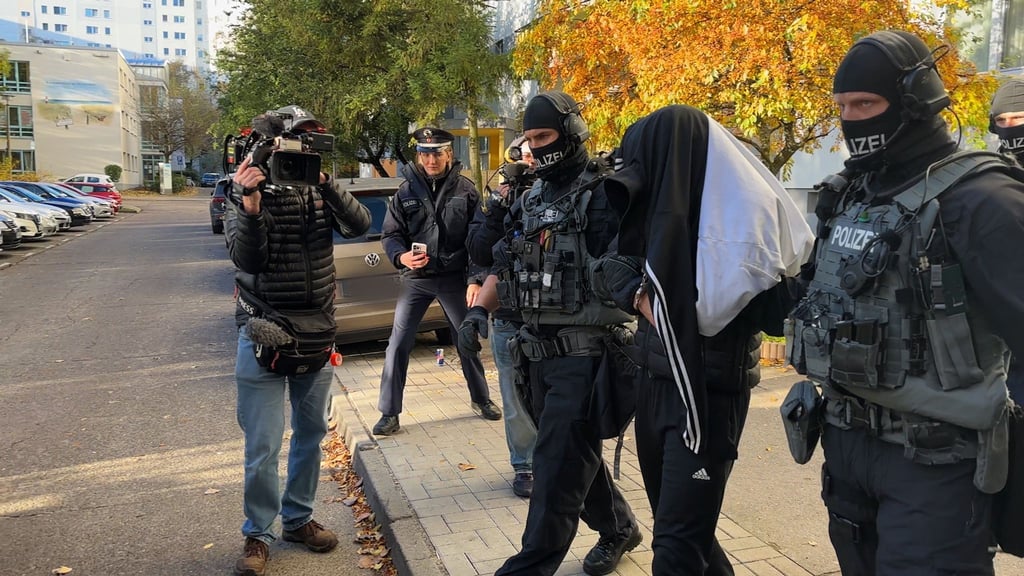 Spezialkräfte verlassen mit einer festgenommenen Person ein Haus in Weißensee.
