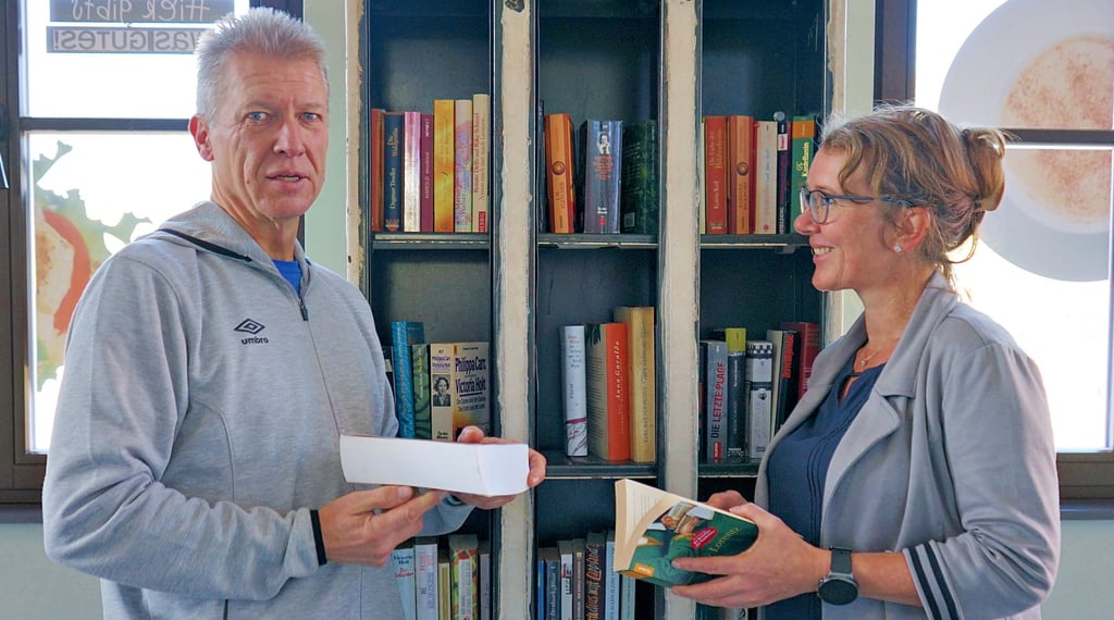 „Lesezauberer“ Torsten Gatzsche und Standortleiterin Doreen Hauck bestücken die alten Schaltschränke im Bahnhof, die nun Tauschregale sind.