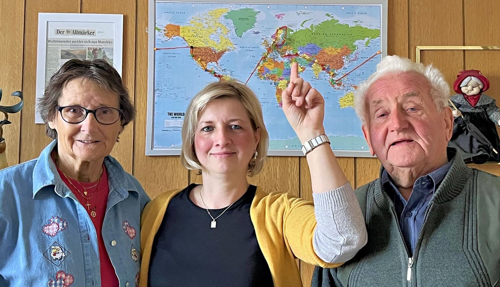 Helga, Karina und Günther Zersch unter der Weltkarte, auf der alle Stationen ihres Enkels und Sohnes mit Wollfäden und Pins markiert sind. Aktuell ist er in Nepal, zeigt Karina Zersch.