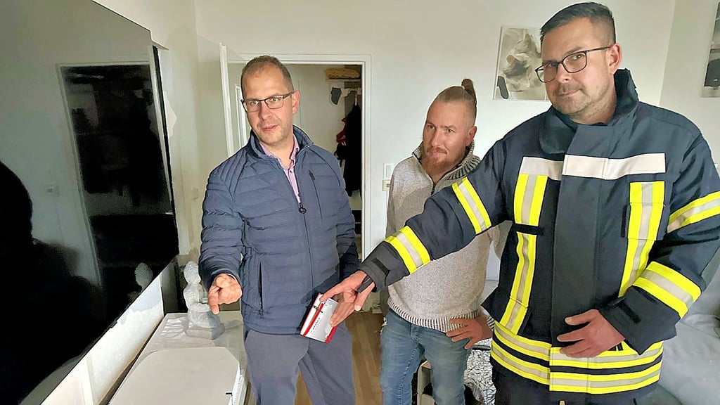 Eine Rußschicht hat sich im Zimmer einer Wohnung im Burger Südring abgesetzt, wie Bürgermeister Philipp Stark, Ortswehrleiter Jens Wiedemann und Familienvater André zeigen.