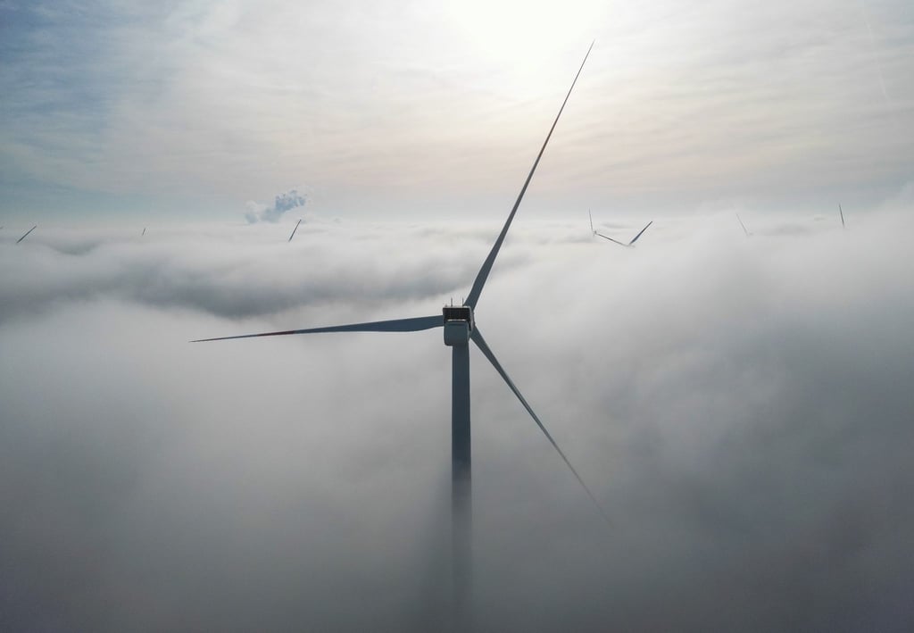 Die Windräder in einem Windpark westlich von Halle ragen aus dem Morgennebel hervor.