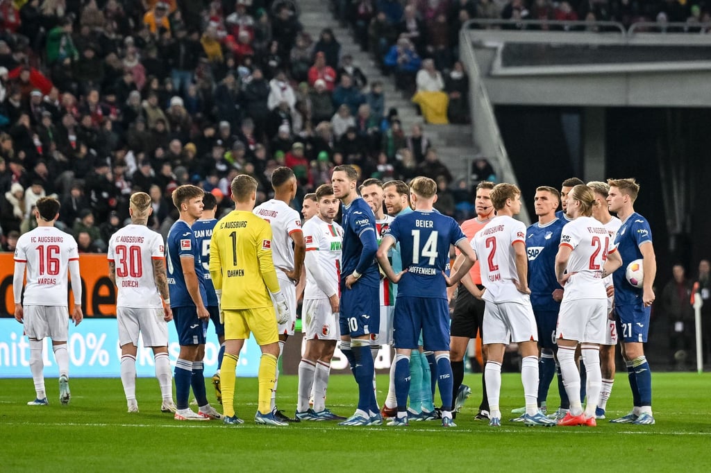 Schiedsrichter Felix Brych bespricht sich mit den Spielern am Mittelkreis.