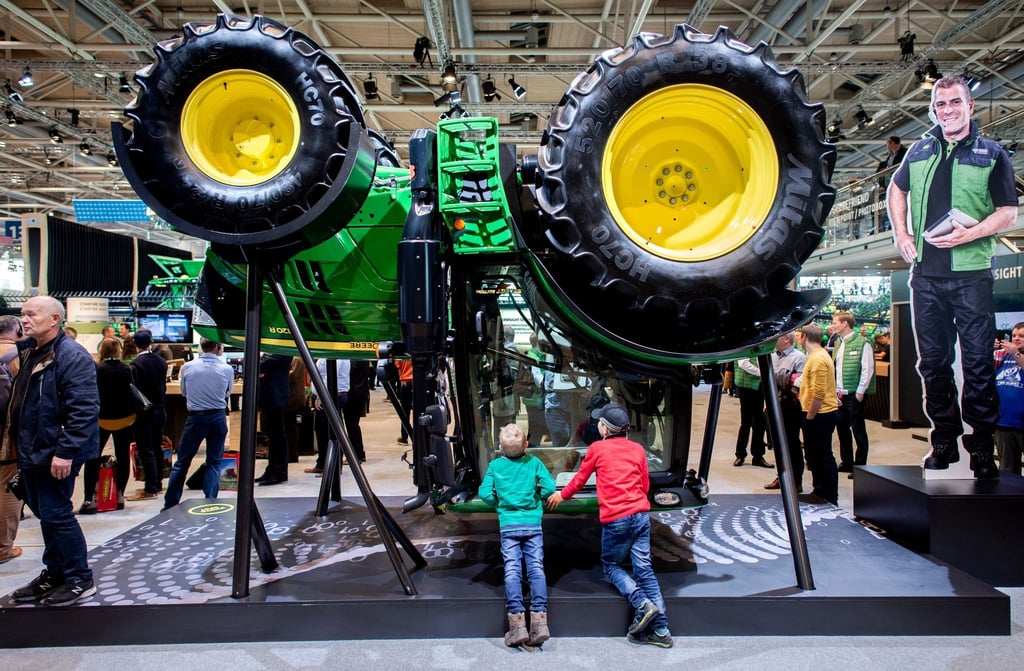 Zwei Jungen betrachten am Stand von John Deere auf der Landtechnik-Messe Agritechnica in der Messe Hannover einen Traktor, der für die Präsentation umgedreht wurde.