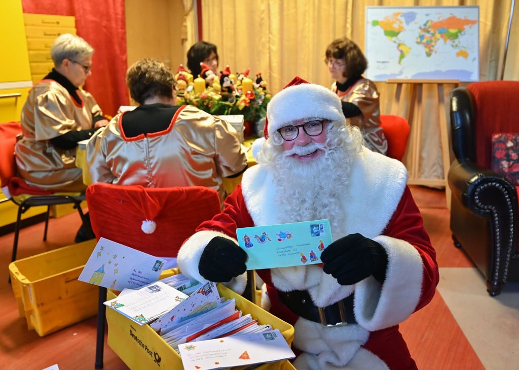 Der Weihnachtsmann hält im Weihnachtspostamt einen von vielen Briefen mit Wunschzetteln in den Händen.