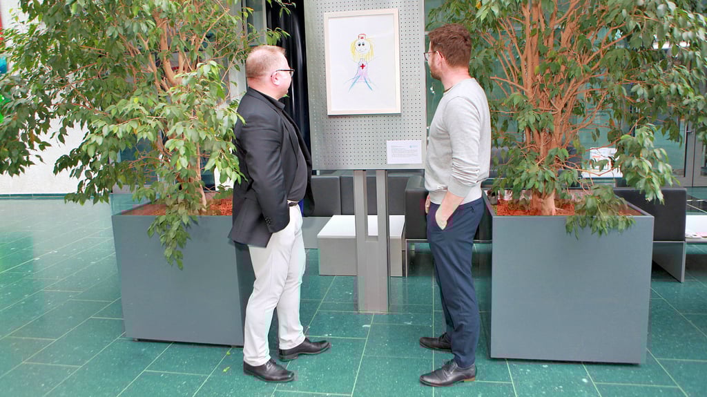 René Rottleb (l.) und Bernhard Spring vom Goitzsche Klinikum bewundern ein berührendes Kinderbild mit einer gemalten Krankenschwester, beide sind beeindruckt von der kreativen Ausdrucksweise der kleinen Künstler.