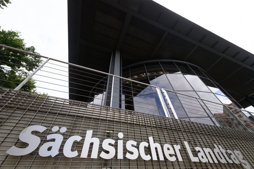 Sächsischer Landtag steht an einem Gitter am hintern Teil des Parlamentsgebäudes.