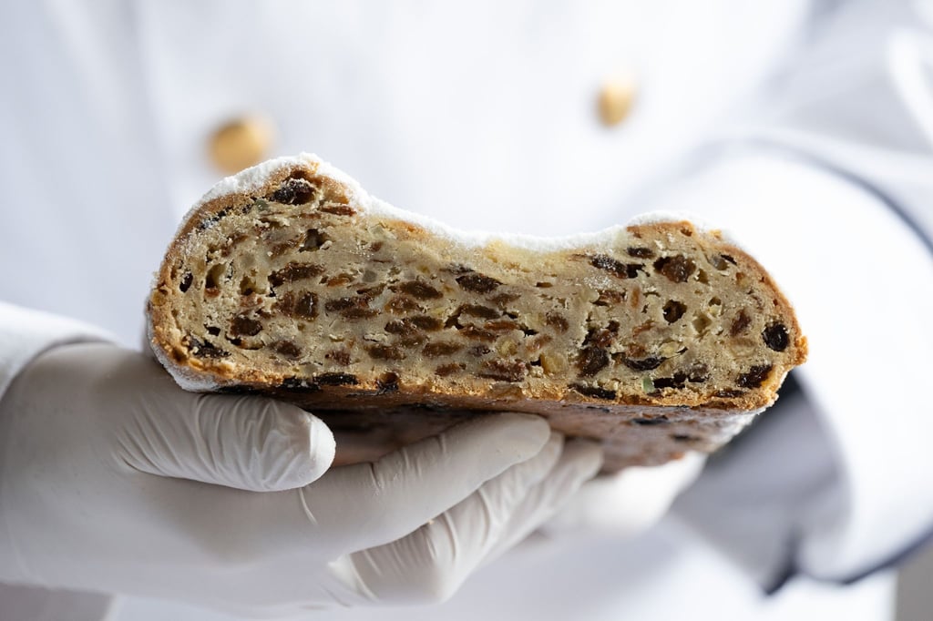 Ein Prüfer hält einen Christstollen in der Hand.
