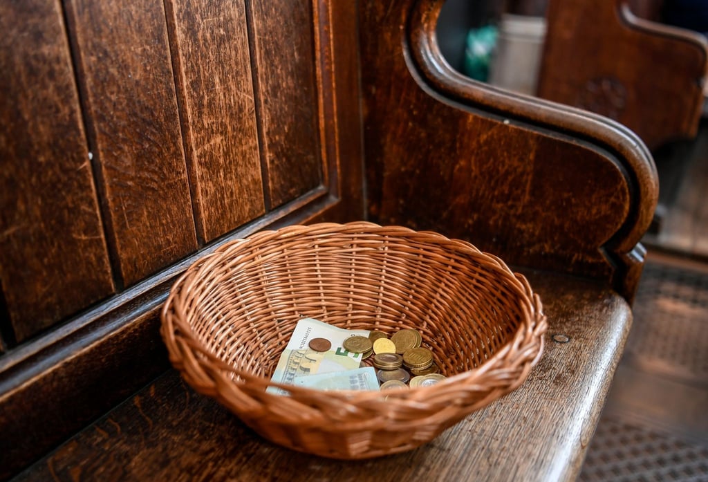 Ein Korb mit Geldscheinen und Münzen steht in einer Kirche.