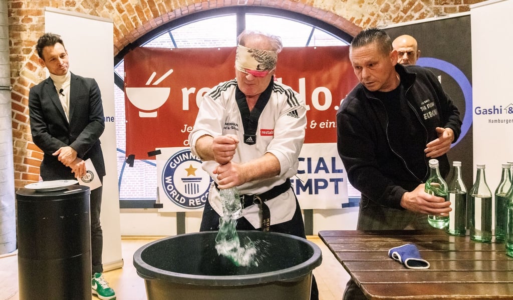 Der Kampfsportler Muhamed Kahrimanovic beim Versuch, mit verbundenen Augen und einem rohen Ei in der Hand Glasflaschen zu zerschlagen.