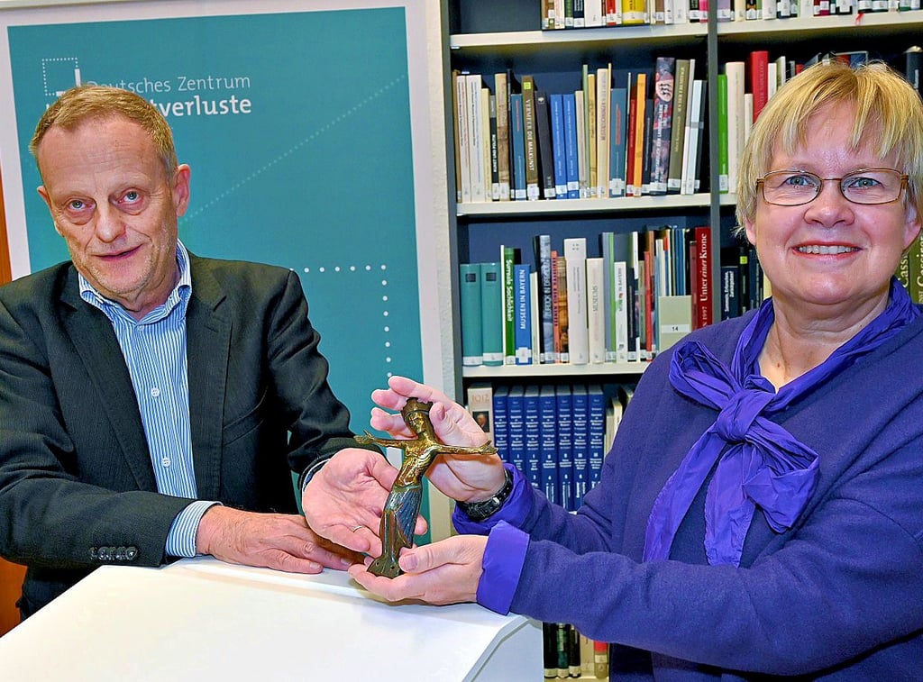 Imke Gielen nimmt für die Nachkommen von Ottmar Strauss das Kruzifix aus den Händen von Kulturgutverluste-Vorstand Gilbert Lupfer.