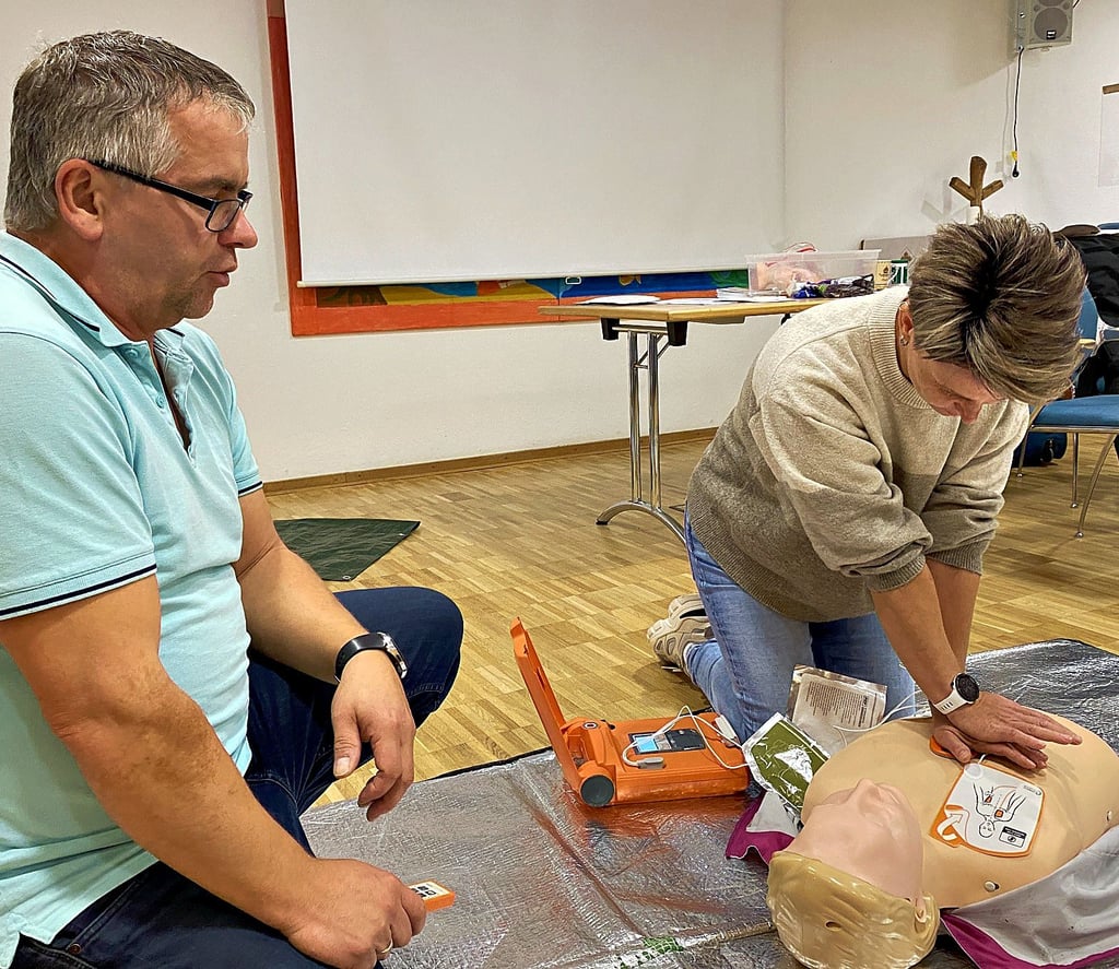 Michael Guse erklärt Mitarbeiterin Nicole Linke den Umgang mit einem Defibrillator.