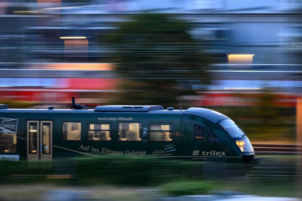 Ein Trilex Zug der Länderbahn fährt am Morgen auf einem Gleis entlang.