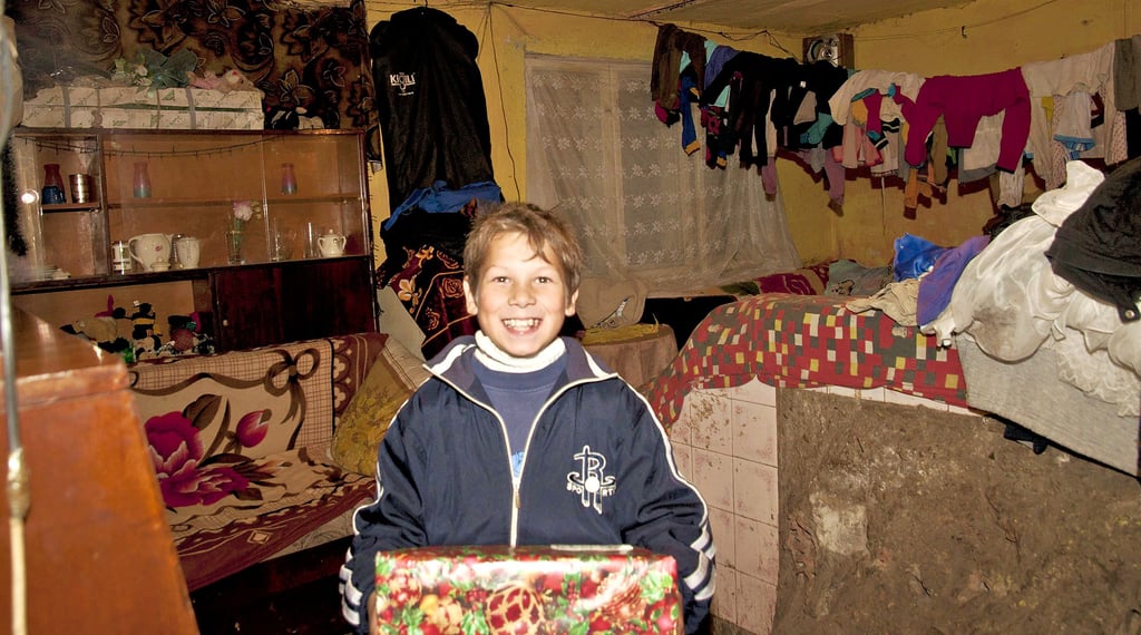 Ein Junge in Rumänien freut sich über ein Geschenk, das er vom Weihnachtspäckchenkonvoi bekommen hat.