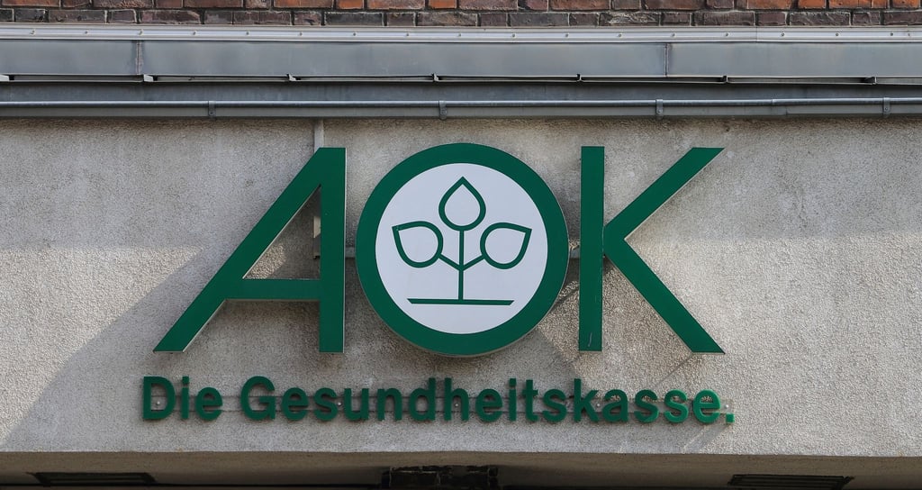 Blick auf das Logo der Krankenkasse AOK an einem Gebäude.