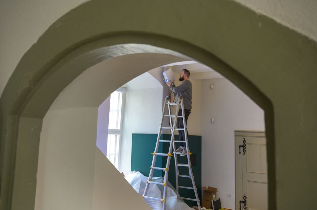 Im Geburtszimmer von Hardenberg montiert ein Mitarbeiter Multimediatechnik.