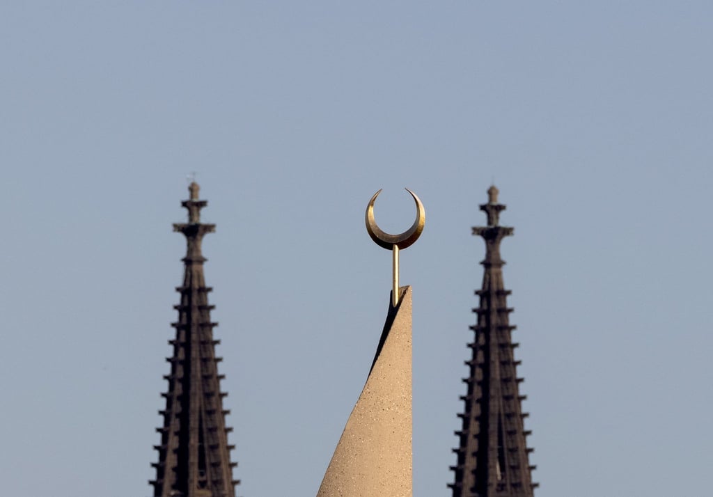 Der Halbmond auf einer Moschee ist zwischen den Türmen des Kölner Doms zu sehen. Der Auftritt eines hochrangigen afghanischen Taliban-Funktionärs in einer Kölner Moschee löst harsche Kritik aus.