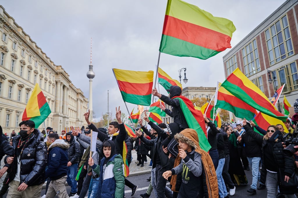 Demonstranten schwenken in Berlin-Mitte gelb-rot-grüne Flaggen.