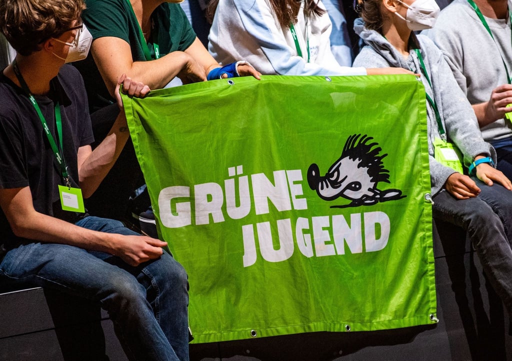 Ein Banner der Grünen Jugend wird von Teilnehmern auf einem Kongress gehalten.