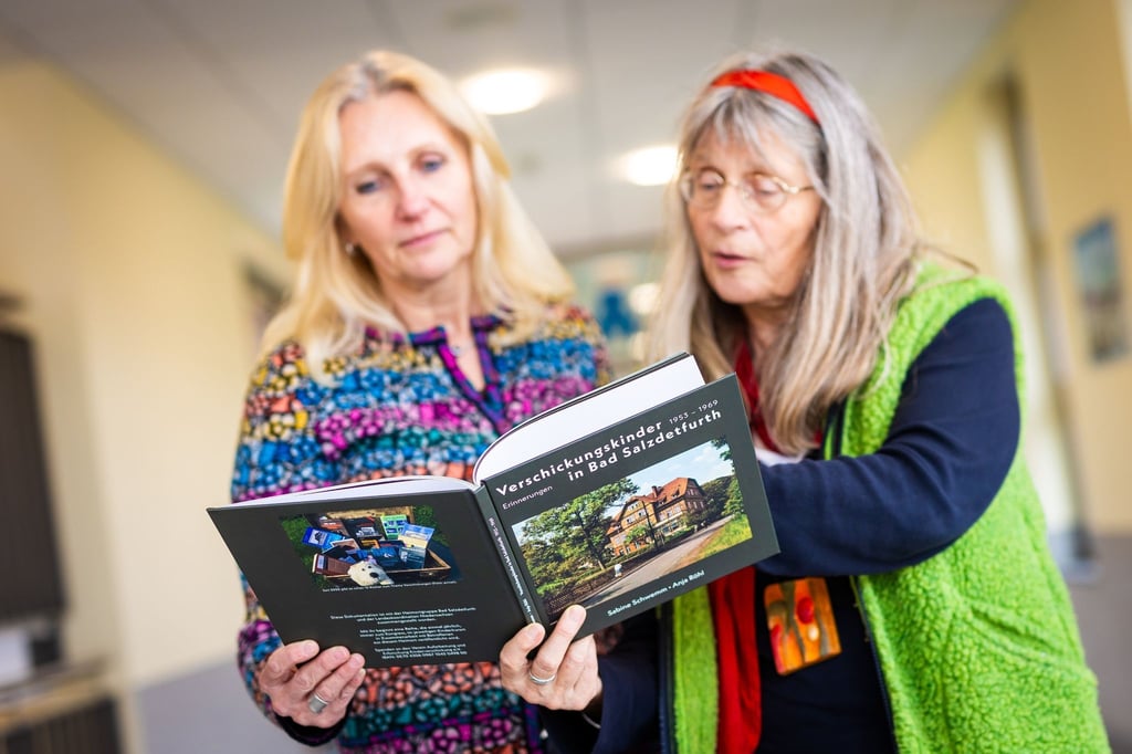 Sabine Schwemm (l) und Anja Röhl (r) blättern am Rande vom Bundeskongress „Aufarbeitung Kinderverschickungen“ in dem Buch „Verschickungskinder in Bad Salzdetfurth“.