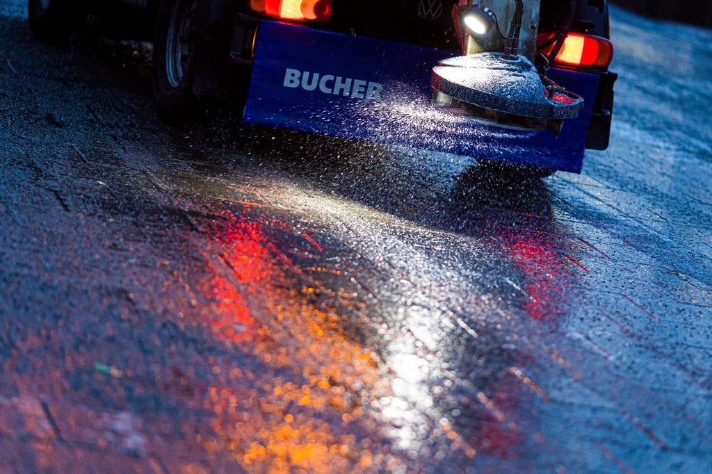Ein Streufahrzeug verteilt Streumittel auf der Straße.