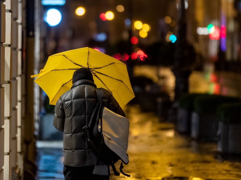Ein Passant geht bei Regen durch die Stadt.