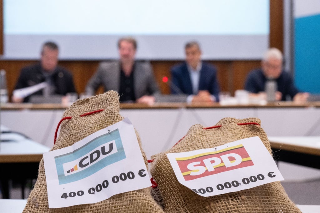 Zwei Säckchen, auf denen „CDU 400.000.000 €“ und „SPD 400.000.000 €“ steht.