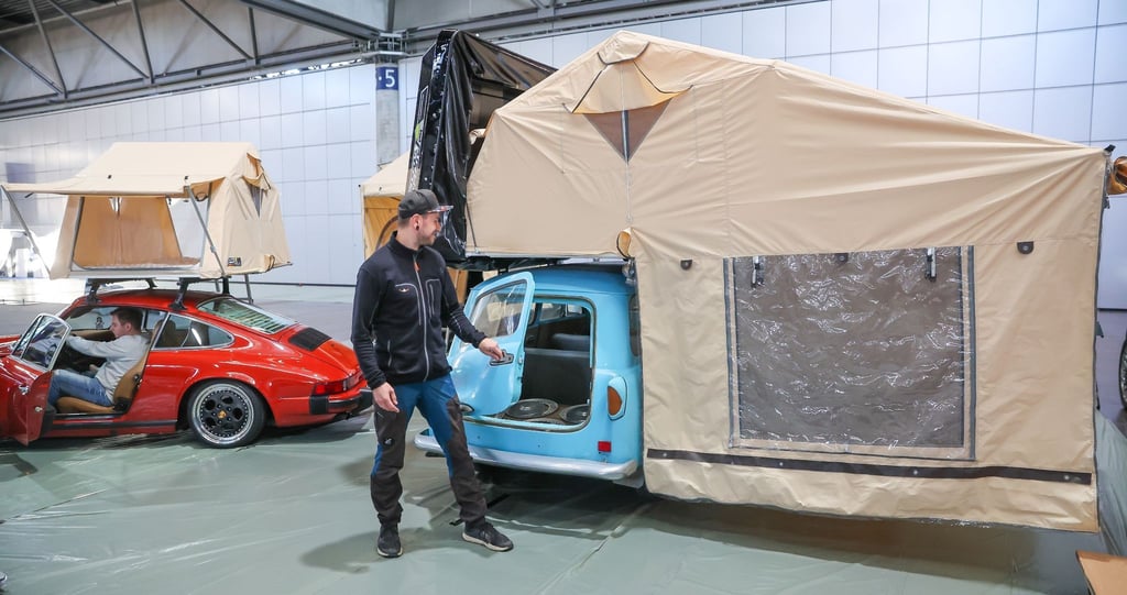 Ein Mitarbeiter schließt die Hecktür eines Trabant 500 Kombi mit einem riesigen Dachzelt.