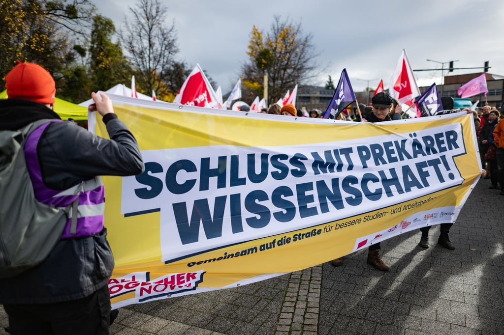 Teilnehmer stehen im Rahmen des bundesweiten Hochschulaktionstages mit einem Banner „Schluss mit prekärer Wissenschaft!“.