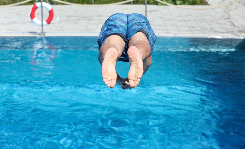 Ein Mann springt in einem Schwimmbad ins Wasser.