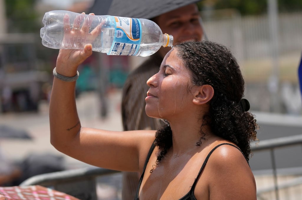 Ein Fan von Taylor Swift kühlt sich vor dem Konzert der „Eras“-Tour vor dem Olympiastadion in Rio de Janeiro mit Wasser ab.