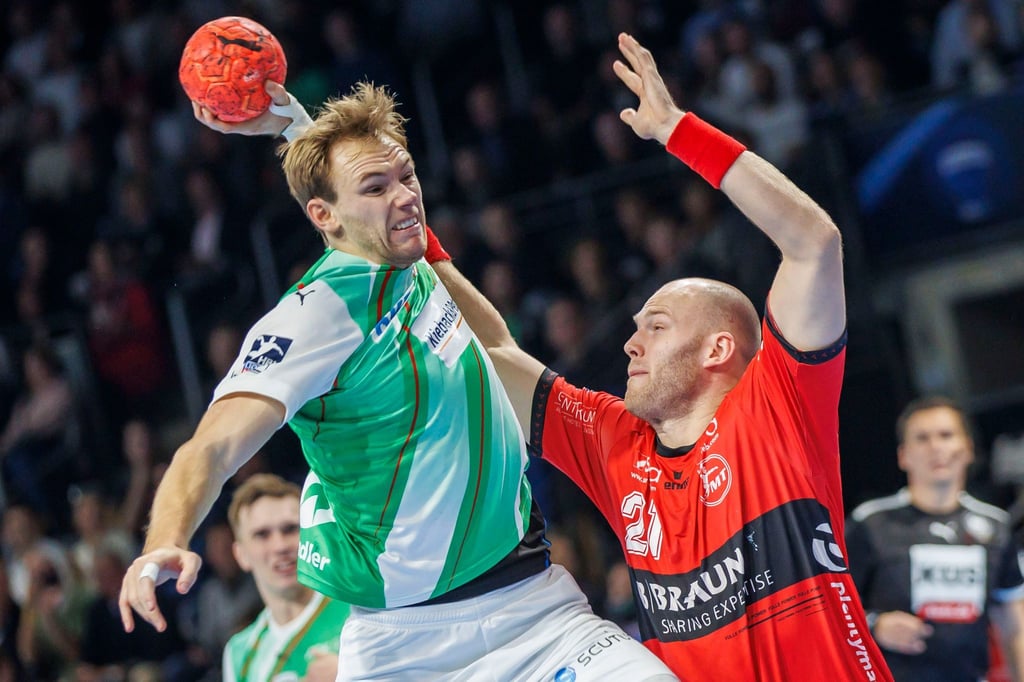 Berlins Mathias Gidsel (l) wirft den Ball auf das Tor.