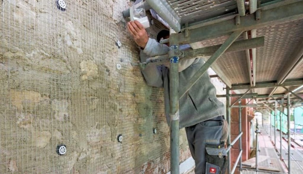 Ein Arbeiter ist mit der Sanierung eines Gebäudes beschäftigt.