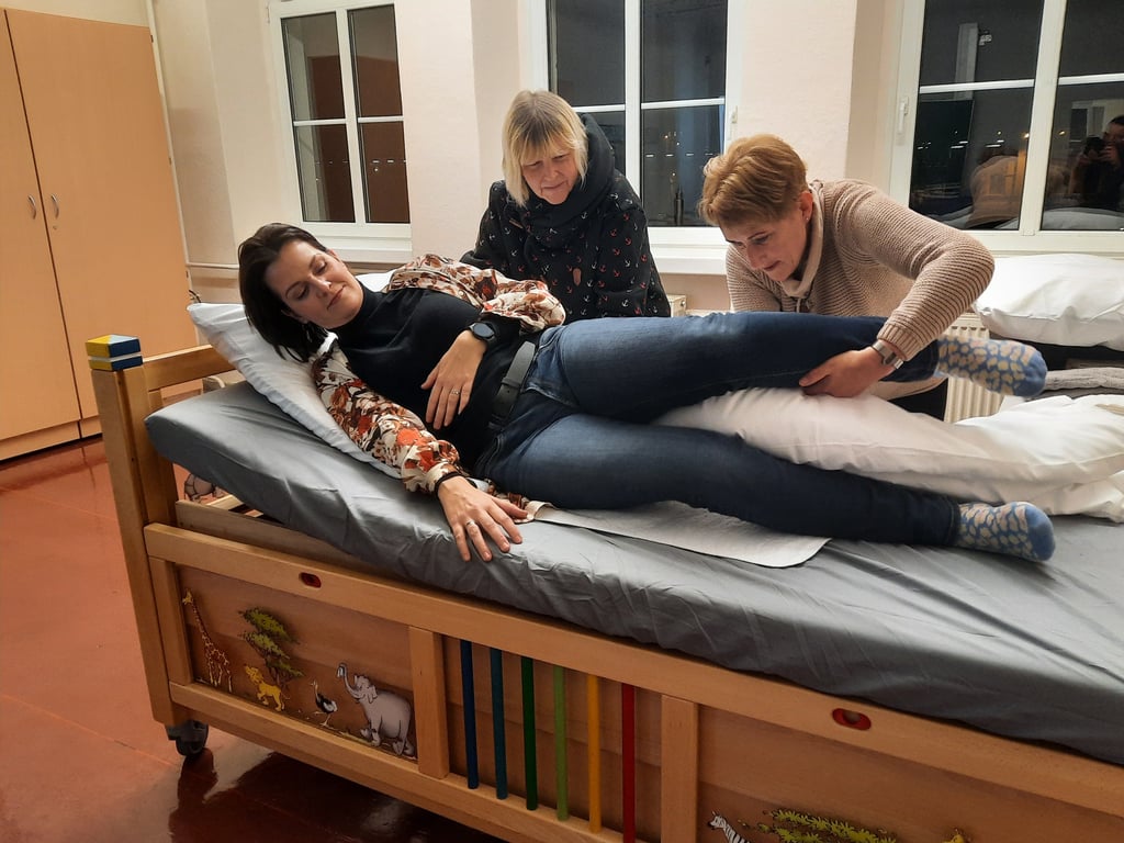 Kursleiterin Annekathrin Reinhardt (rechts) zeigt den Teilnehmerinnen Evelyn Krümmling und Carina Schöppe, die als Versuchsperson fungiert, wie man pflegebedürftige Menschen am besten und gefahrlosesten aus dem Bett hilft.