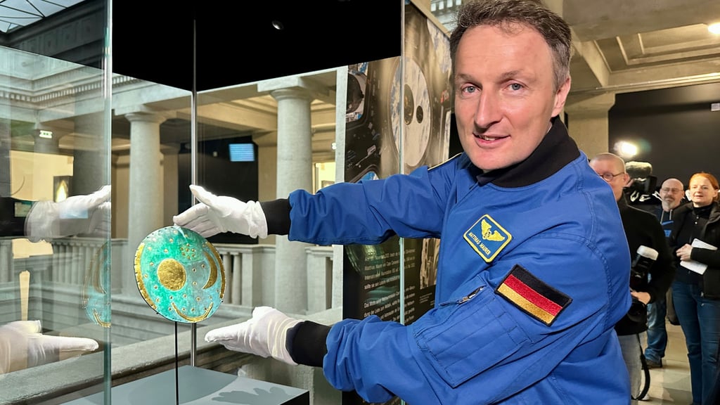 Mit Handschuhen platziert Astronaut Matthias Maurer die Kopie der Himmelsscheibe in einer Vitrine. Dort ist sie bis zum 5. Mai zu sehen.