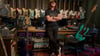 Der Rush-Frontmann Geddy Lee steht in seinem Studio, Bassgitarren hängen an der Wand.