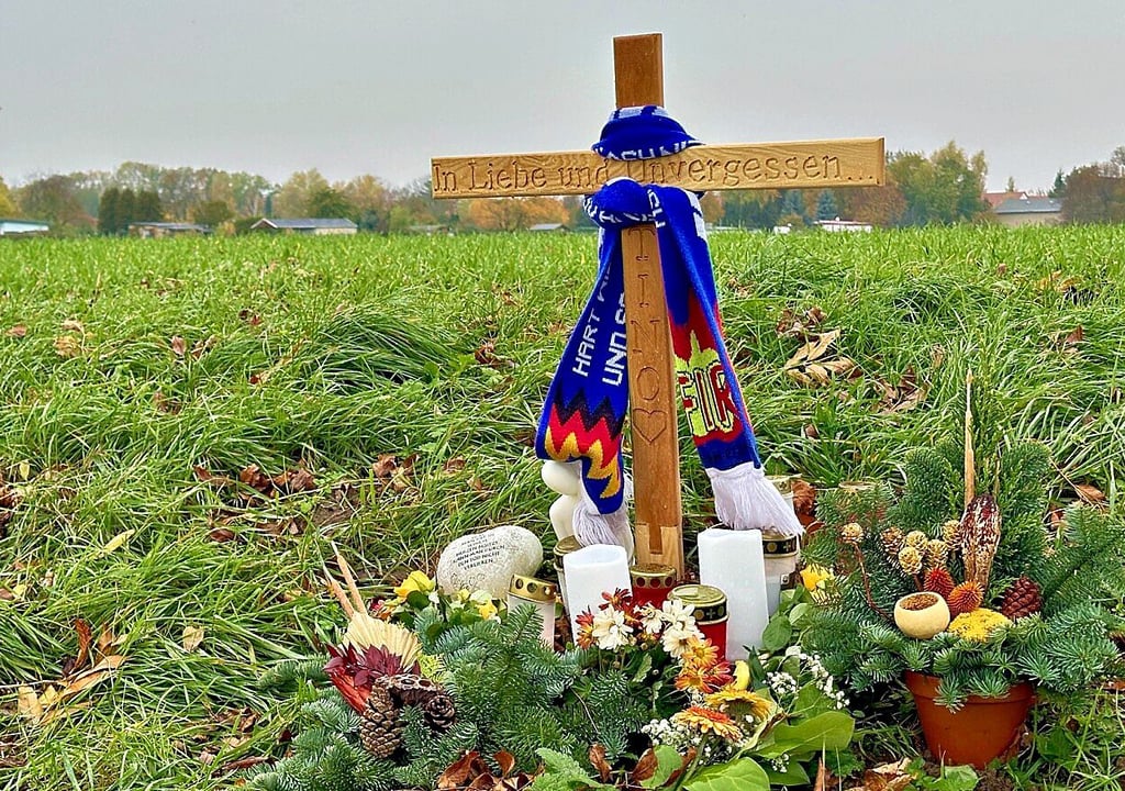 Ein Kreuz erinnert am Tatort an den getöteten Tino E. Freunde und Bekannte haben am Feldweg Blumen abgelegt und Kerzen aufgestellt.