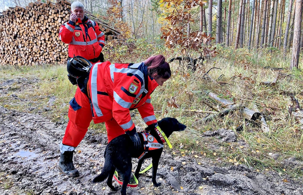 Der Einsatz beginnt: Hundeführerin Lisa Kleinsteuber von der Rettungshundestaffel Burgenlandkreis stattet Rettungshund Jani mit einer sogenannten Kenndecke aus, damit er im Gelände zu hören ist. Über Funk gibt hingegen Steffen Berthel den Start des Einsatzes durch.