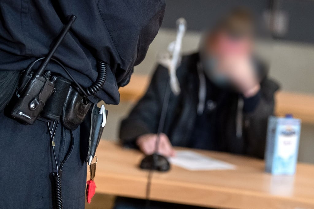 Einer der Angeklagten (r) sitzt vor Prozessbeginn in der Stadthalle Verden.