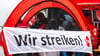 Ein Banner mit der Aufschrift „Wir streiken!“ ist bei einer Warnstreikkundgebung zu sehen.