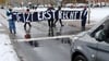 Mitglieder der „Letzten Generation“ blockieren während des Prozesses in Stralsund eine Straße.