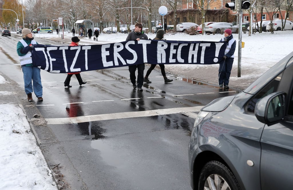 Mitglieder der „Letzten Generation“ blockieren während des Prozesses in Stralsund eine Straße.