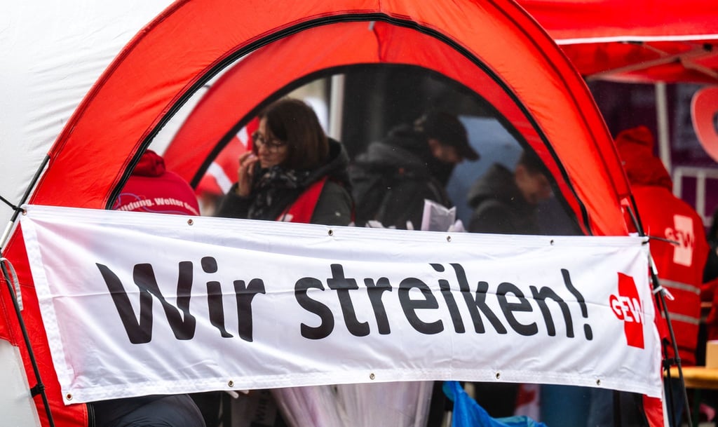 Ein Banner mit der Aufschrift „Wir streiken!“ ist zu sehen.