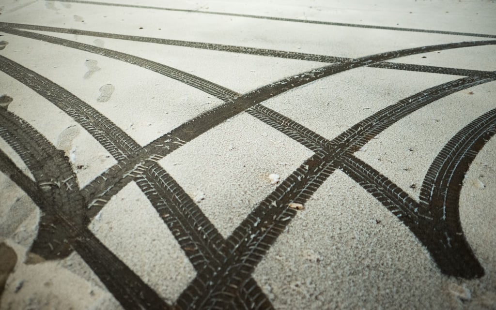 Reifenspuren eines wendenden Autos sind im Schnee zu sehen.