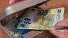 Eine Frau holt Eurobanknoten aus einer kleinen Geldkassette.