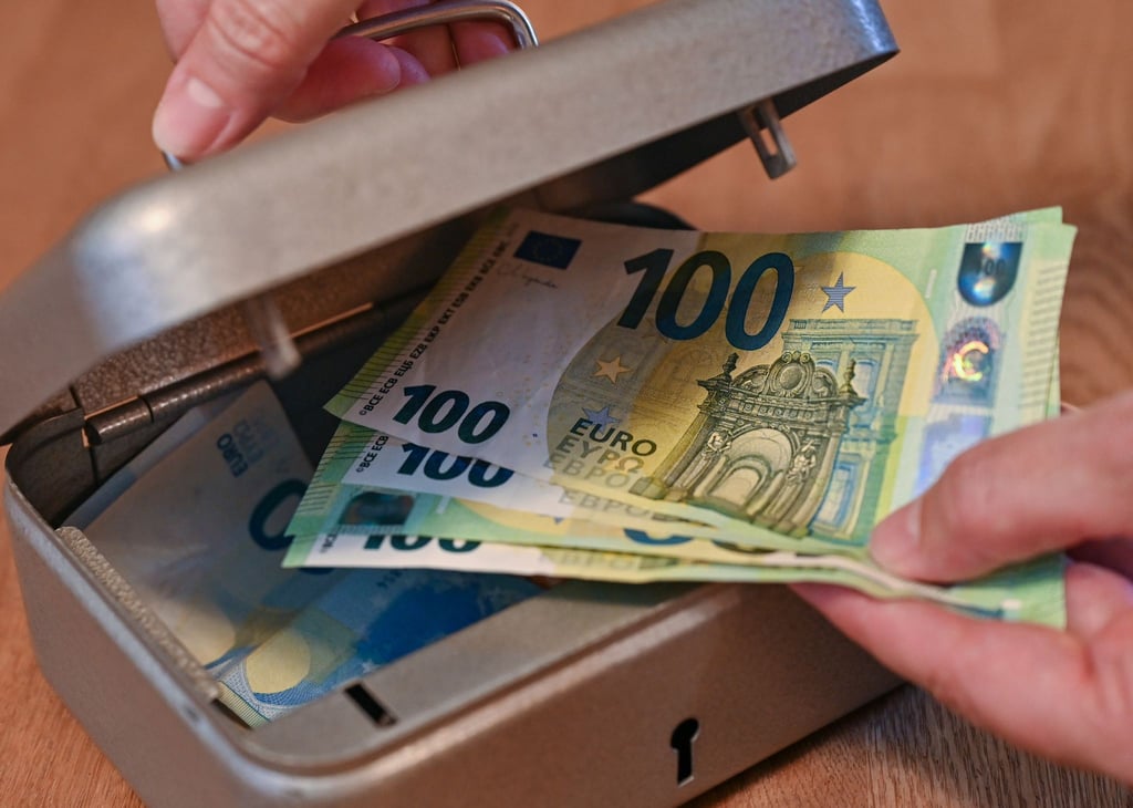 Eine Frau holt Eurobanknoten aus einer kleinen Geldkassette.