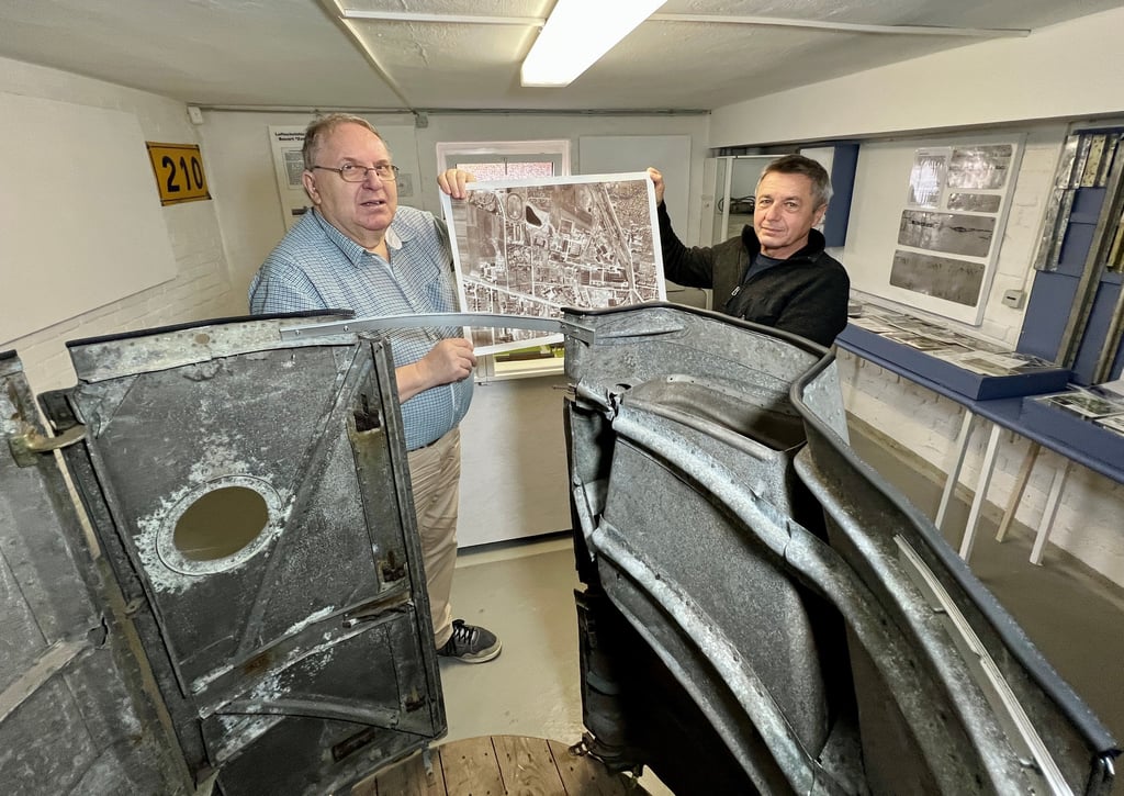 Eberhard Zutz (links) und Dietmar Kuropka zeigen eine Aufnahme des Werksgeländes in Leopoldshall, davor ist eine Original-Tribewerksverkleidung zu sehen.