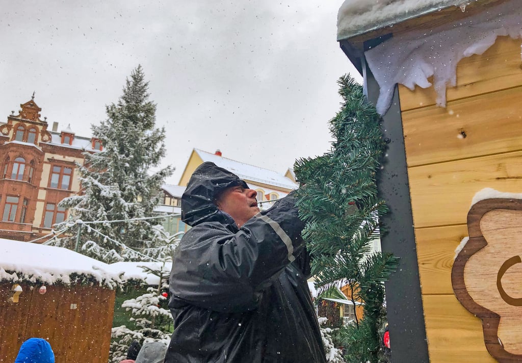 Letzte Vorbereitungen im Flockenwirbel: Angel Romero bringt an seinem Stand eine Tannengrüngirlande an. Am Mittwoch, 29. November, öffnet der Weihnachtsmarkt in Quedlinburg.