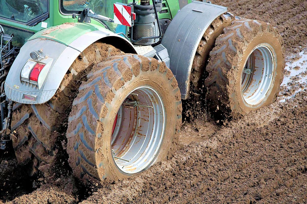 Feldarbeit im Schlamm: Ein Traktor auf einem aufgeweichten Feld.