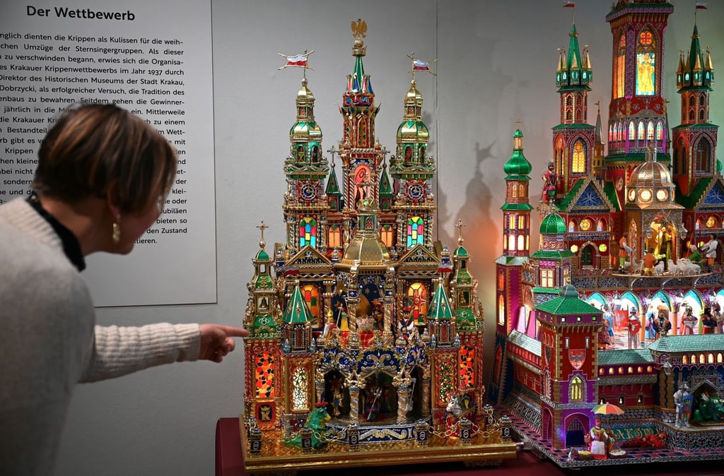 Eine Mitarbeiterin des Stadtgeschichtlichen Museums zeigt auf eine goldene Krakauer Krippe.